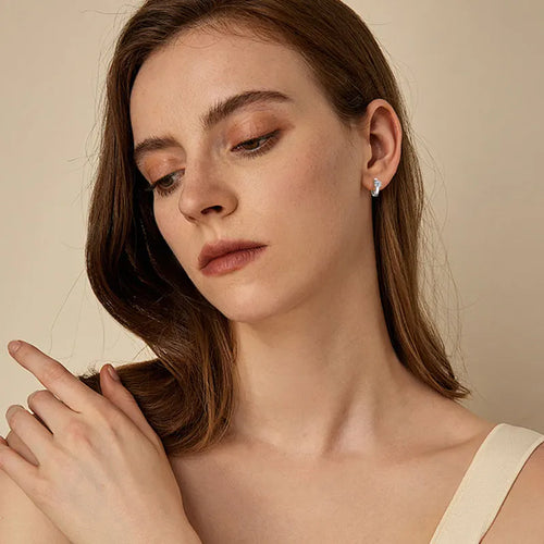 Women's silver huggie hoop earrings with a single sparkling round moissanite stone