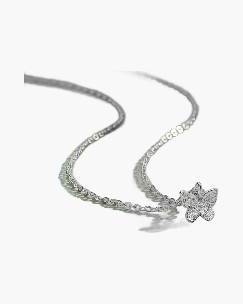 Dainty women's silver 925 necklace with a sparkling cubic zirconia butterfly pendant on green surface