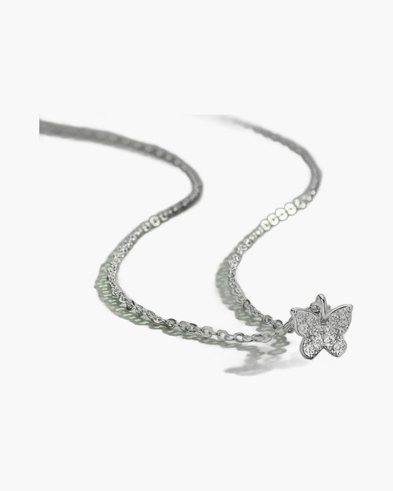 Dainty women's silver 925 necklace with a sparkling cubic zirconia butterfly pendant on green surface