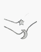 Sparkling silver women's necklaces with star and moon pendants on a blue background