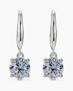 Pair of women's silver dangle earrings with brilliant round solitaire stones in four-prong settings