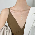 Women's silver 925 necklace with dangling pearls and sparkling accents on a model