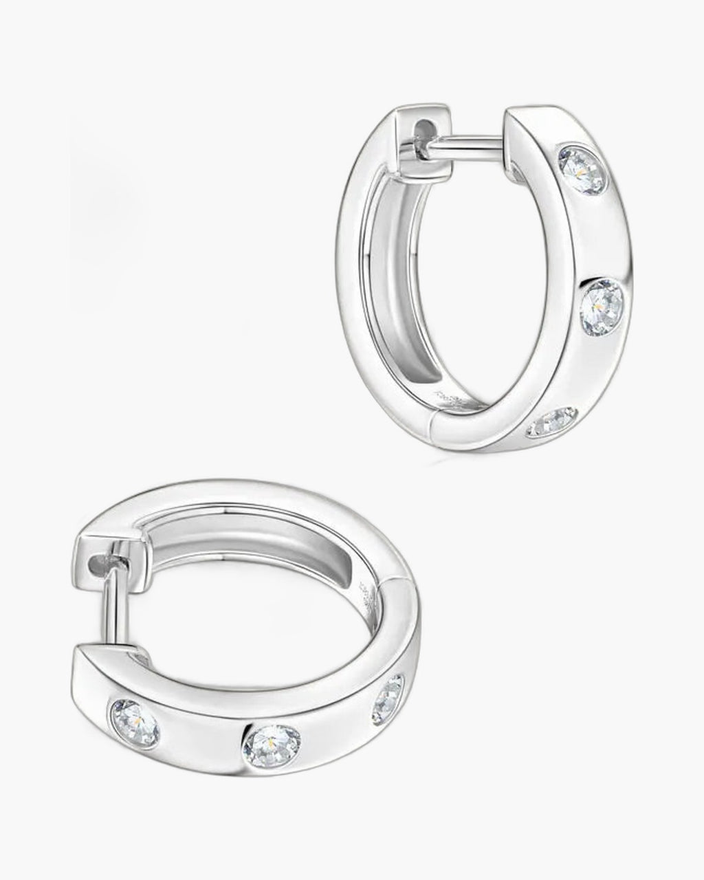 Two women's silver huggie hoop earrings with three bezel-set clear stones each