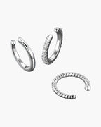 Three women's silver 925 ear cuffs, one with pavé stones, on a blue surface